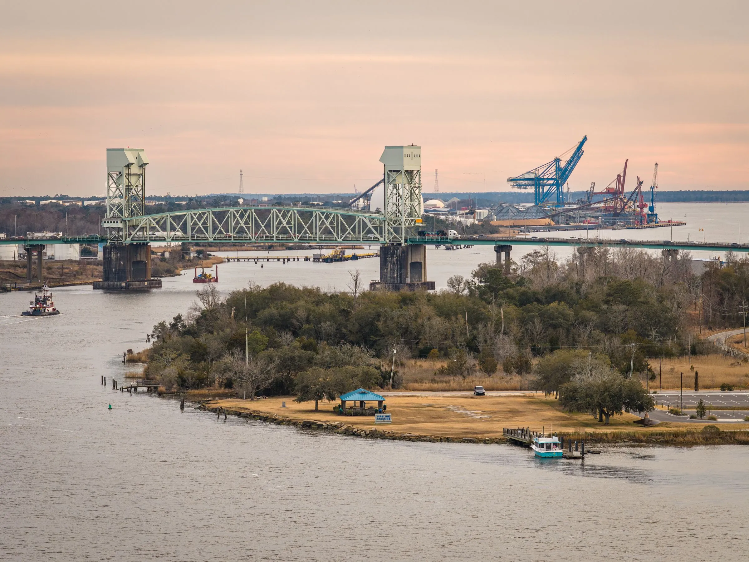 The Cape Fear Memorial Bridge over the Cape Fear River at dusk, with the Port of Wilmington's cranes beyond